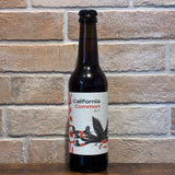 Bouteille California Common bio Soma 33 cl à 5,1 %, étiquette aux oiseaux devant un mur de briques
